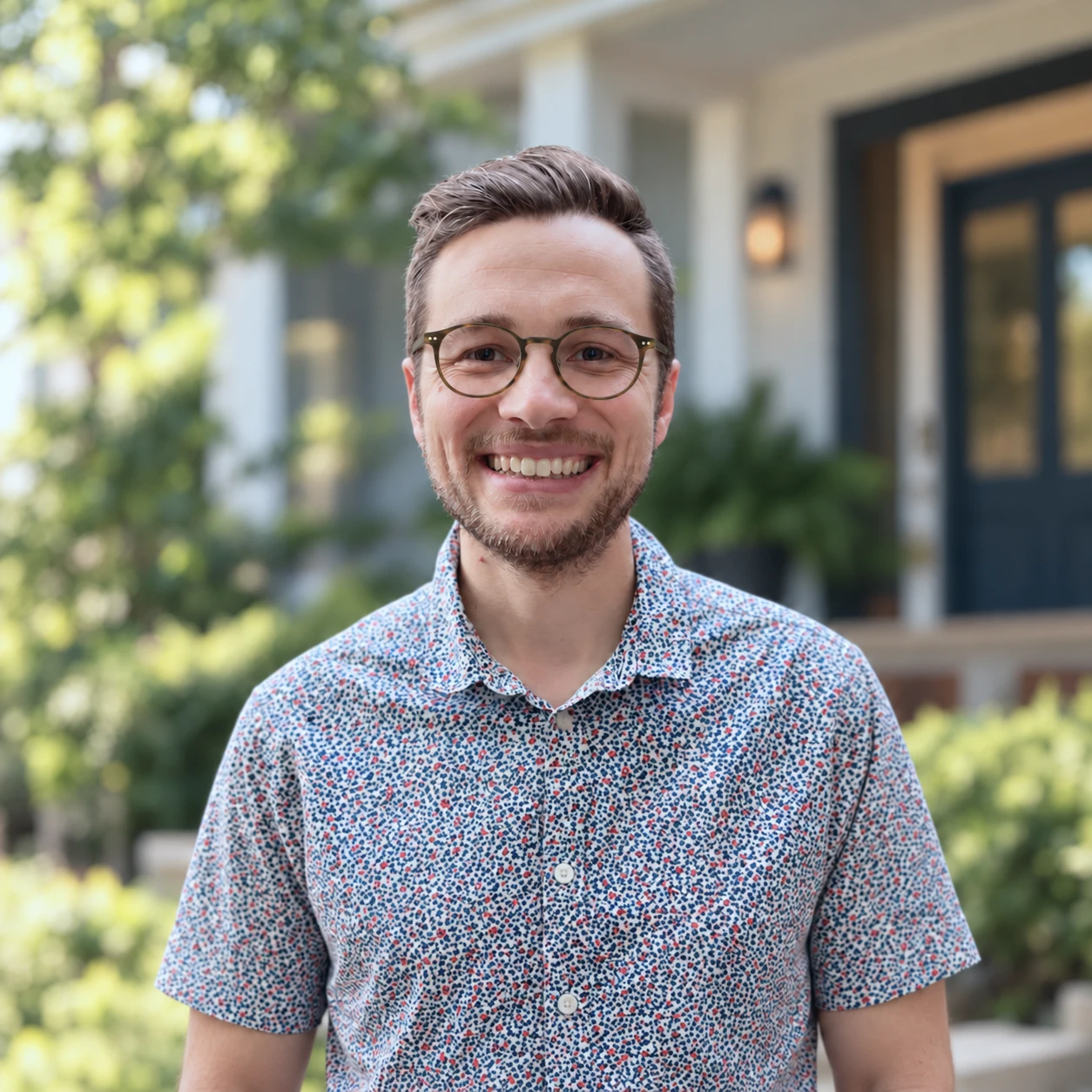 Cameron, smiling, in front of a house with a porch